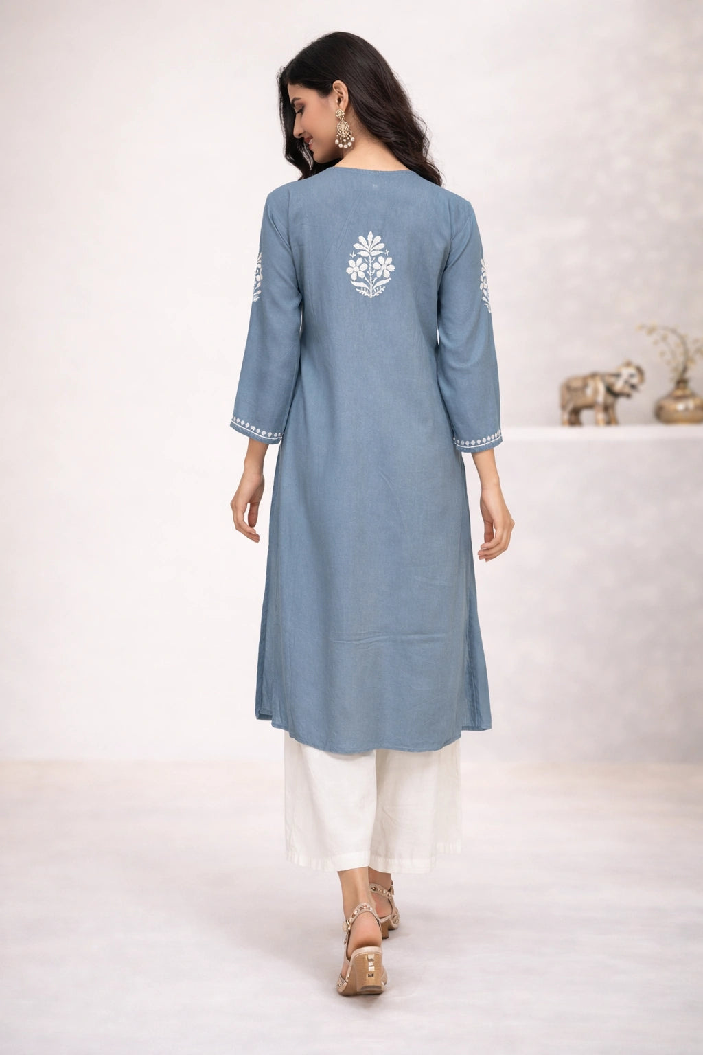 Woman wearing a blue kurta with white embroidery on a white background