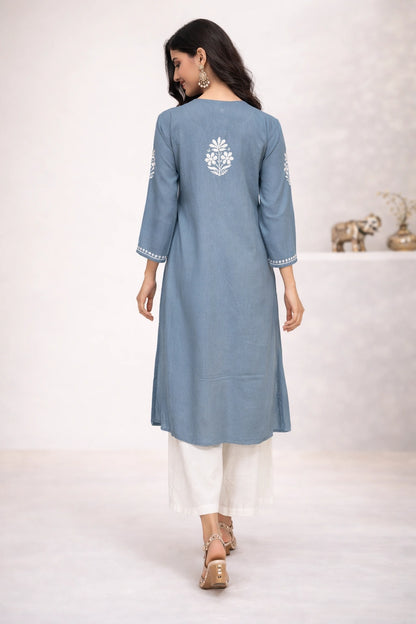 Woman wearing a blue kurta with white embroidery on a white background