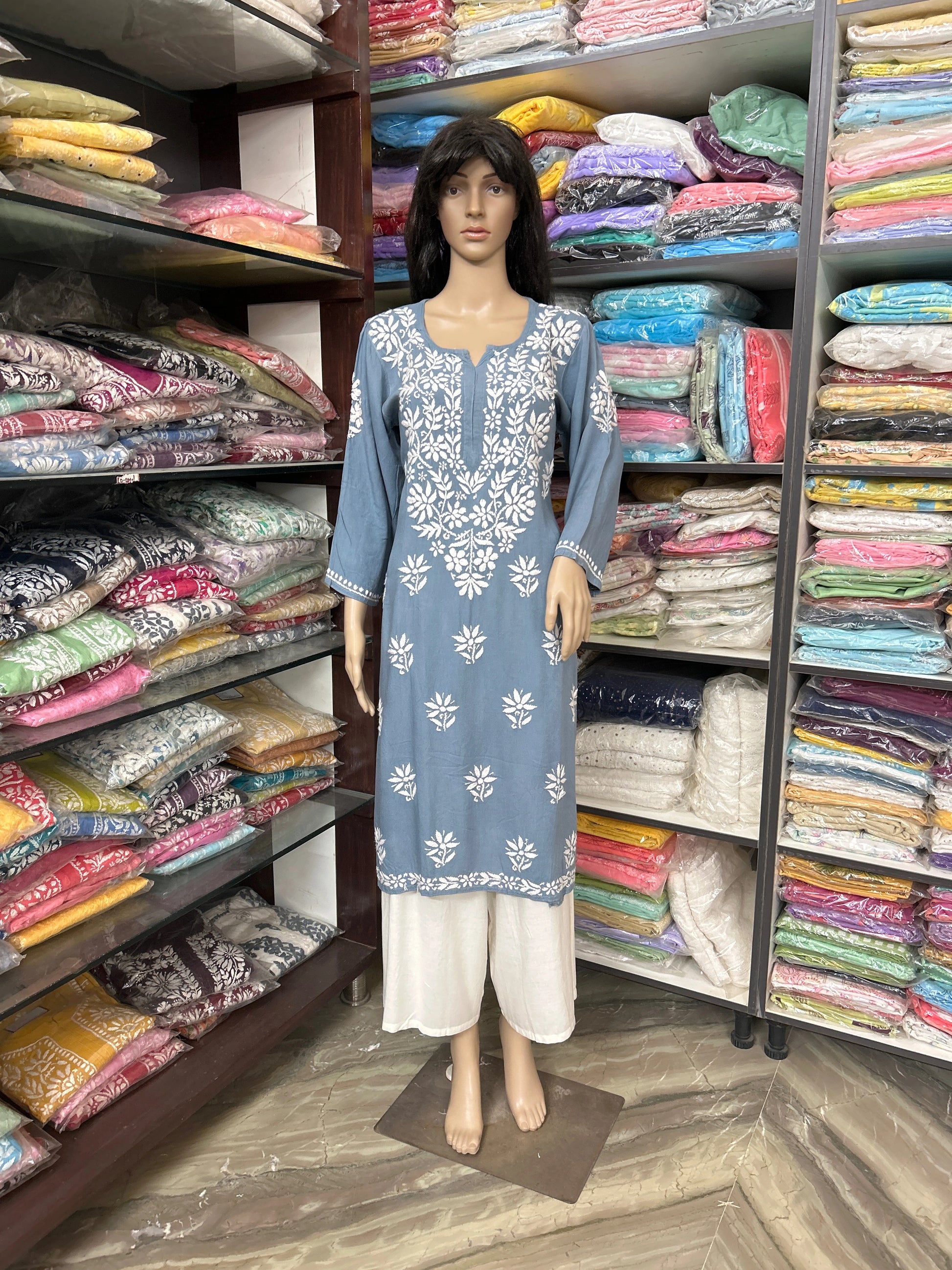 Lucknowi chikankari Mannequin wearing a blue dress with white floral patterns in a fabric store.