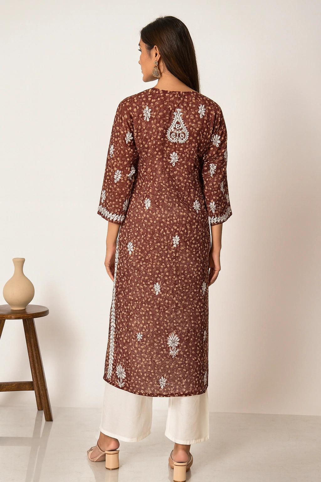 Lucknowi Chikankari Woman wearing a brown floral patterned kurta with white pants on a plain background