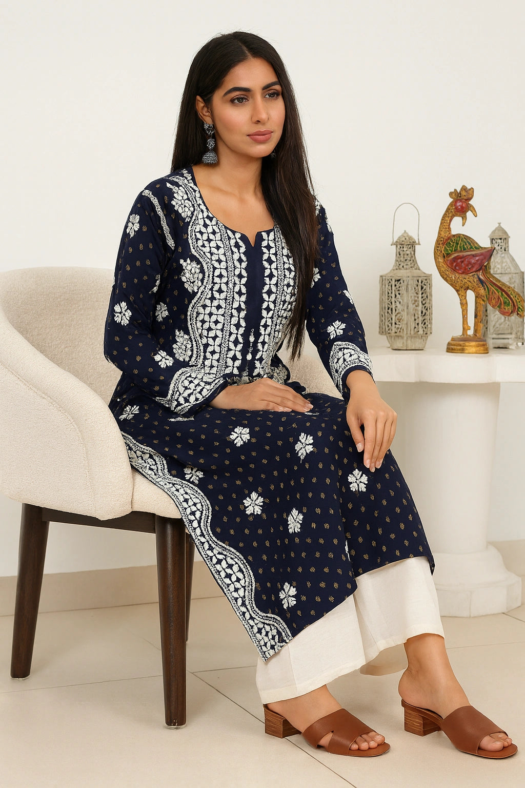 lucknowi chikankari Woman sitting on a chair wearing a navy blue and white patterned kurta with white pants.