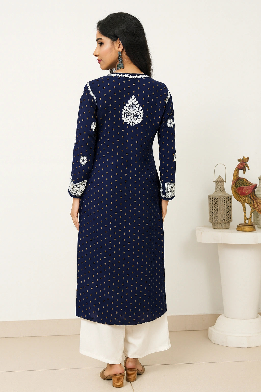 Woman wearing a navy blue embroidered kurta with white pants in a minimalistic room.