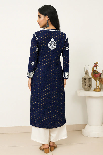 Woman wearing a navy blue embroidered kurta with white pants in a minimalistic room.