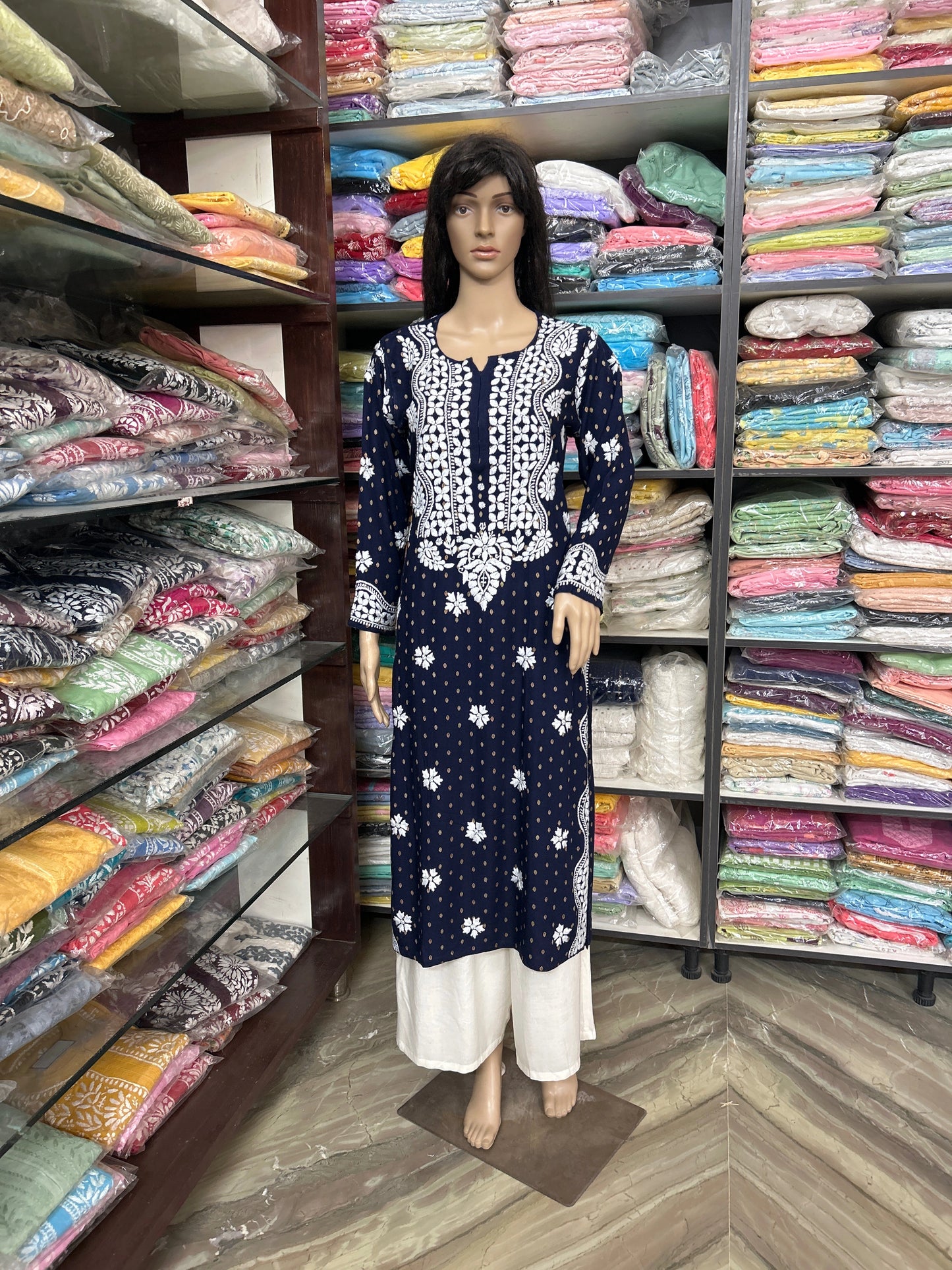 lucknowi chikankari Mannequin wearing a navy blue dress with white patterns in a fabric store.