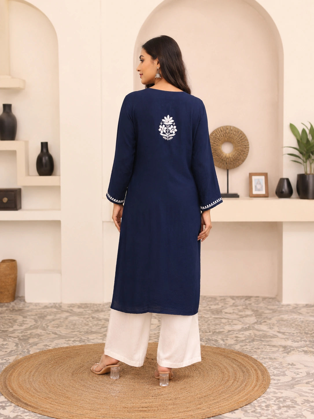 Woman wearing a lucknowi chikankari blue floral kurta with white pants on a white background