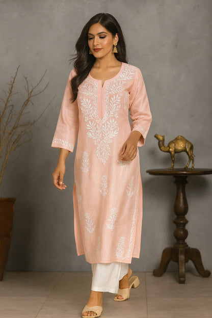 Woman wearing a pink embroidered kurta with white pants against a gray background