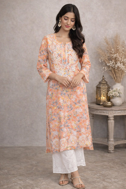 Woman wearing a lucknowi chikankari floral kurta with white pants in a decorated room.