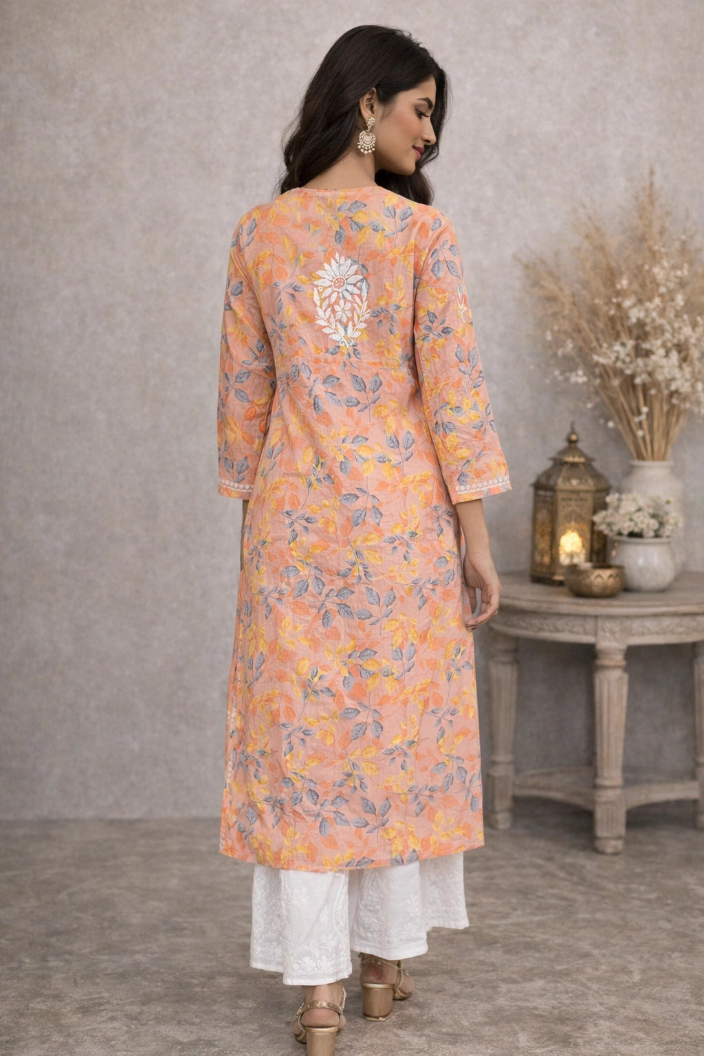 Woman wearing a lucknowi chikankari floral kurta with white pants in a room setting.
