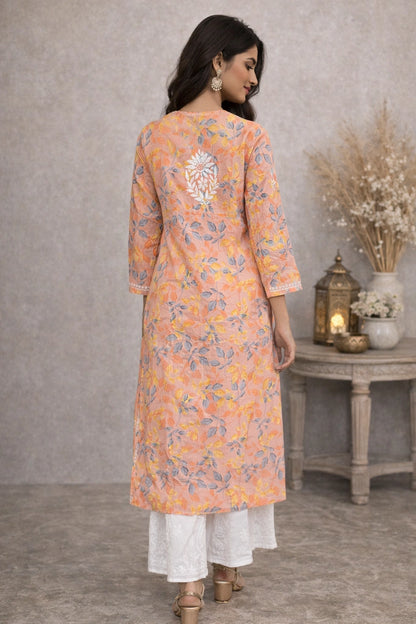 Woman wearing a lucknowi chikankari floral kurta with white pants in a room setting.