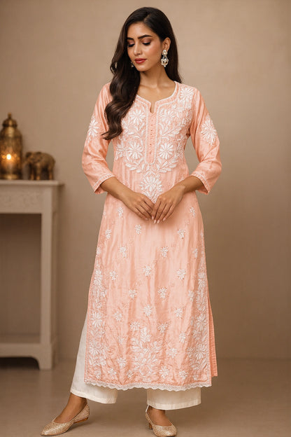Woman wearing a peach embroidered kurta with white pants against a beige background