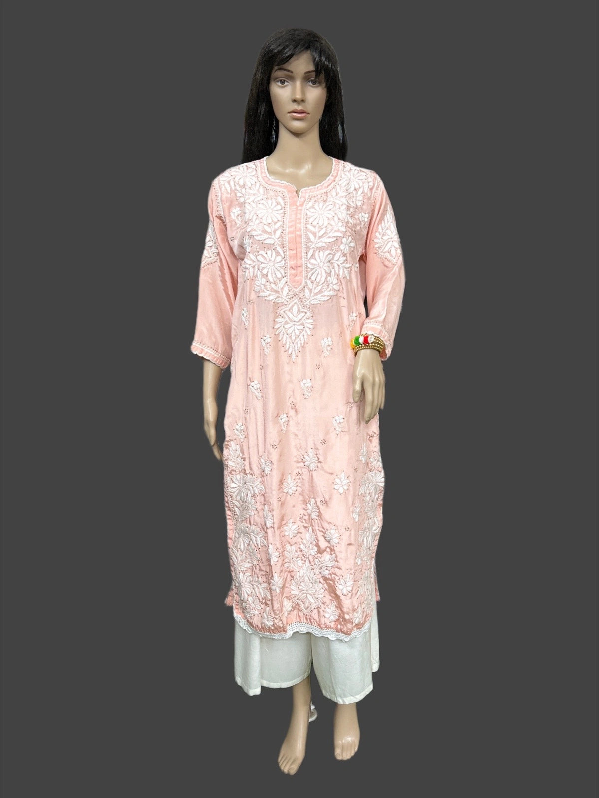 Mannequin wearing a pink embroidered kurta with white pants on a dark background