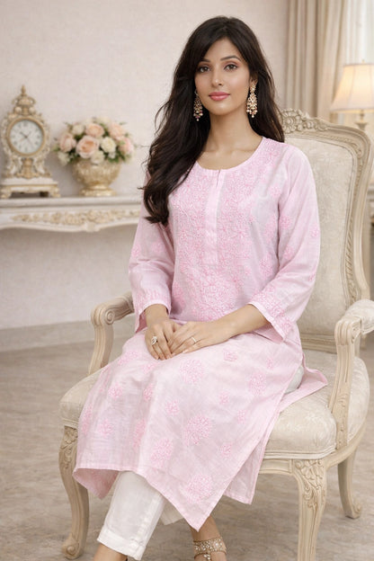 lucknowi chikankari Woman in a pink kurta sitting on an ornate chair in a decorated room.