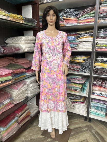 Mannequin wearing a floral dress in a lucknowi chikankari fabric store with shelves of fabric in the background.
