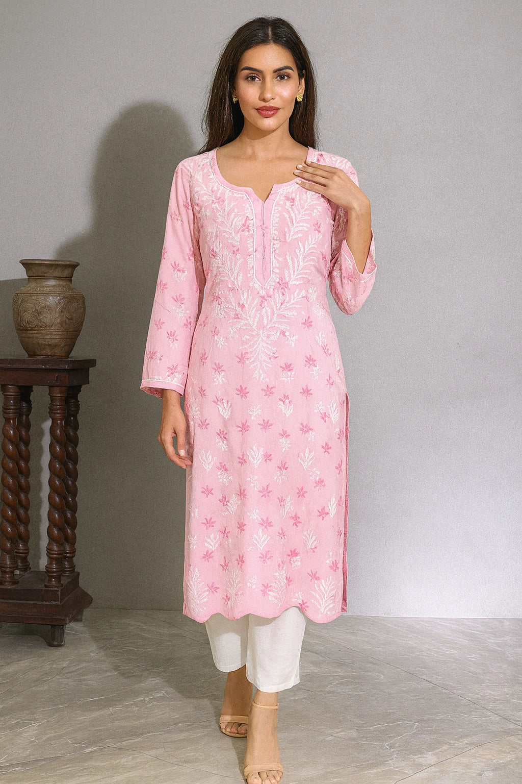 lucknowi chikankari Woman wearing a pink floral kurta with white pants against a gray background