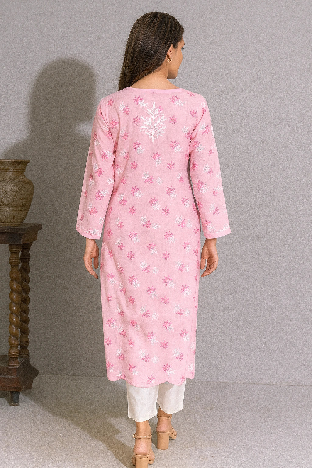 lucknowi chikankari Woman wearing a pink kurta with white floral patterns on a gray background