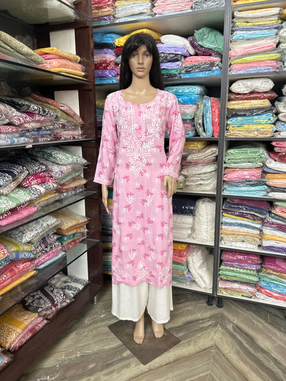 lucknowi chikankari Mannequin wearing a pink dress in a fabric store with shelves of colorful fabrics.
