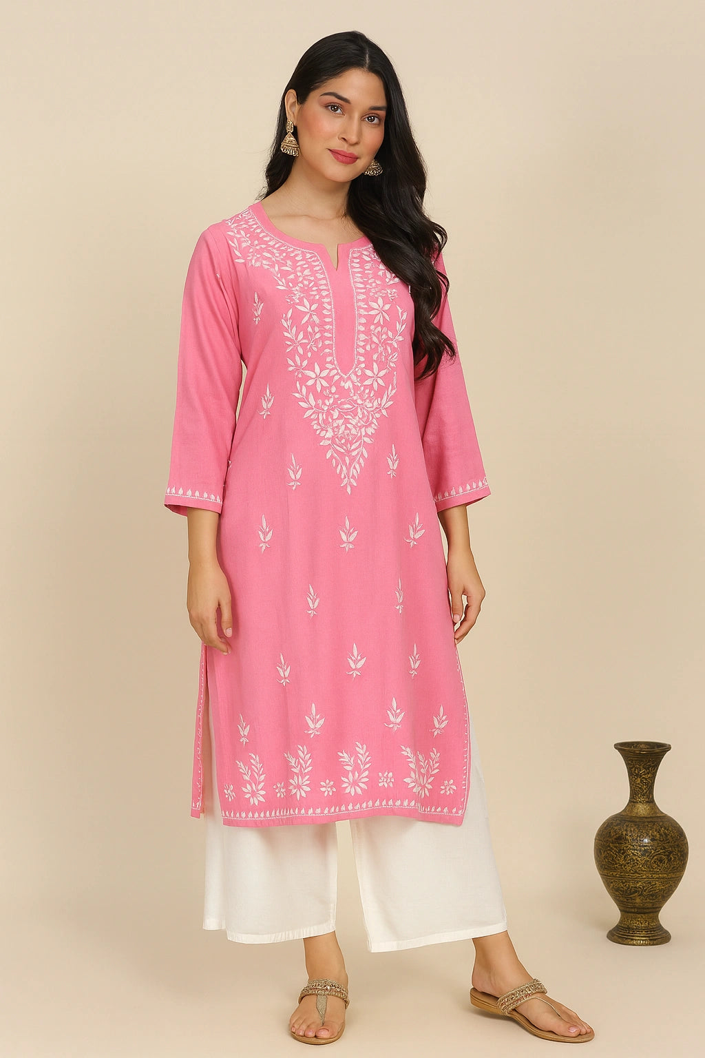 Woman wearing a pink embroidered kurta with white pants against a beige background