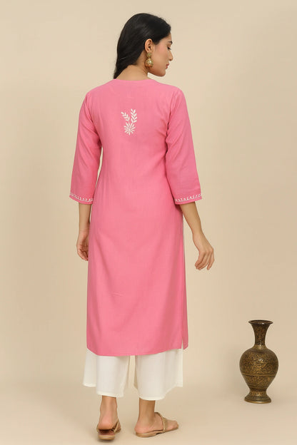 lucknowi chikankari Woman wearing a pink kurta with white pants against a beige background