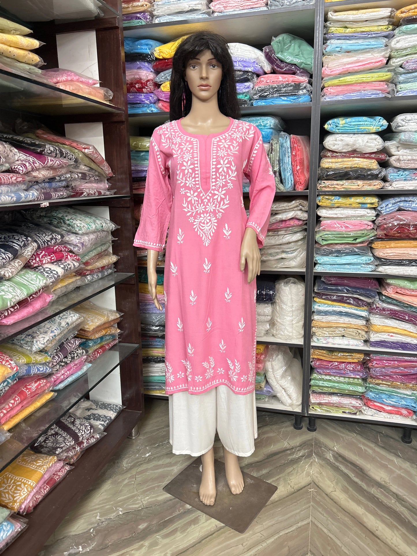 Mannequin wearing a pink embroidered outfit in a fabric store.