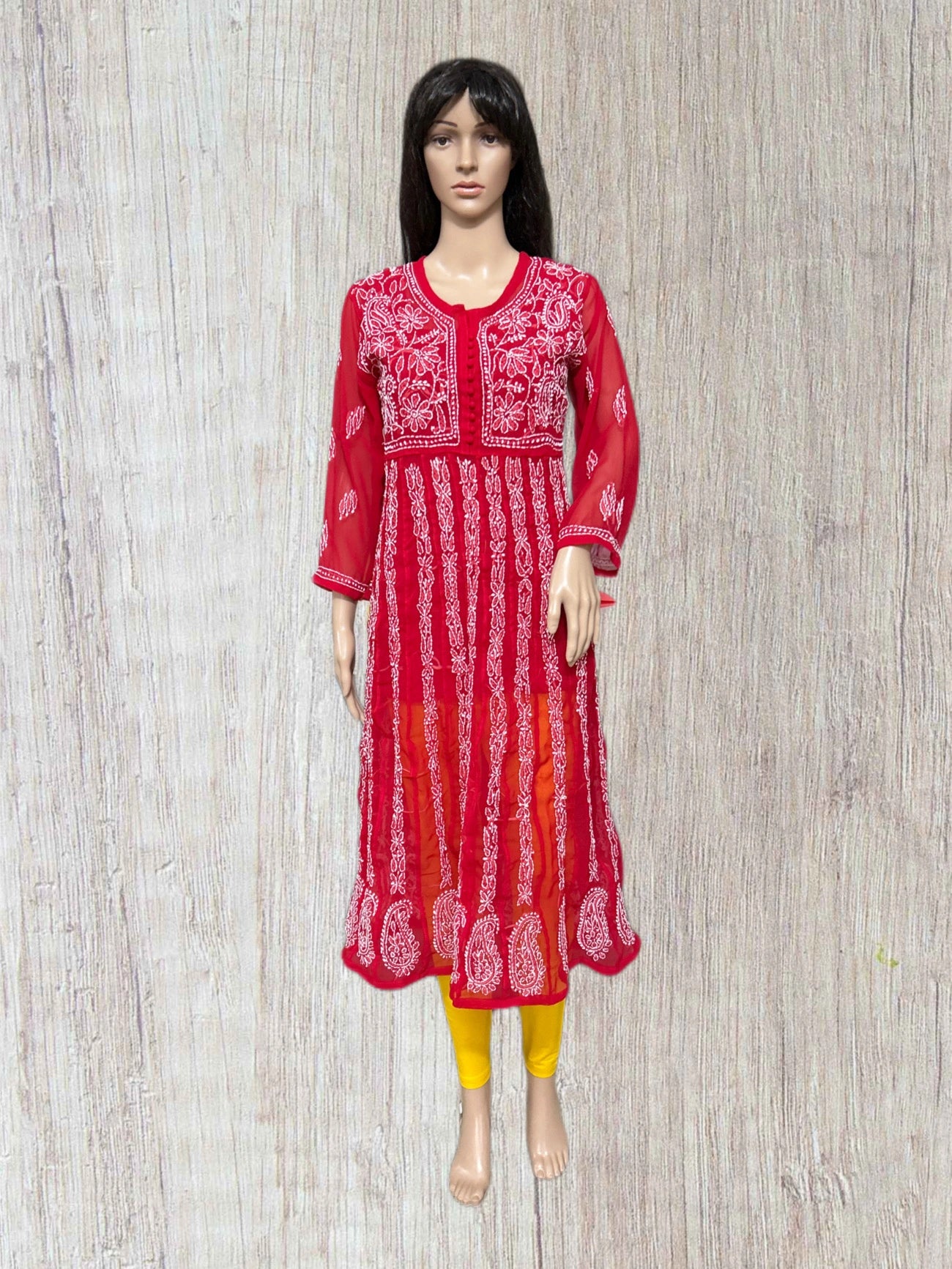 lucknowi chikankari Red and white patterned dress on a mannequin against a wooden panel background