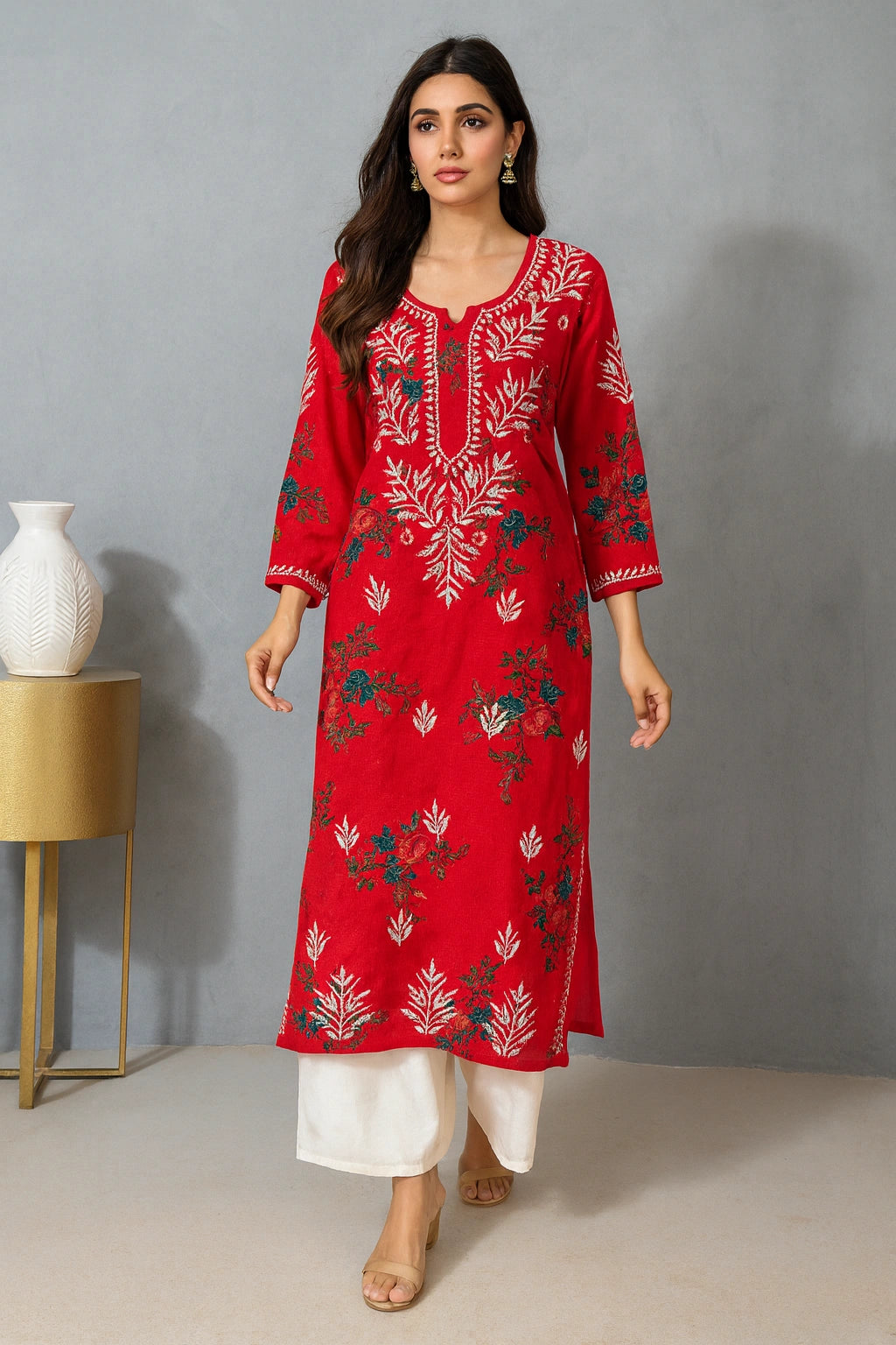 Woman wearing a red embroidered kurta with white pants against a gray background