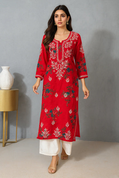 Woman wearing a red embroidered kurta with white pants against a gray background