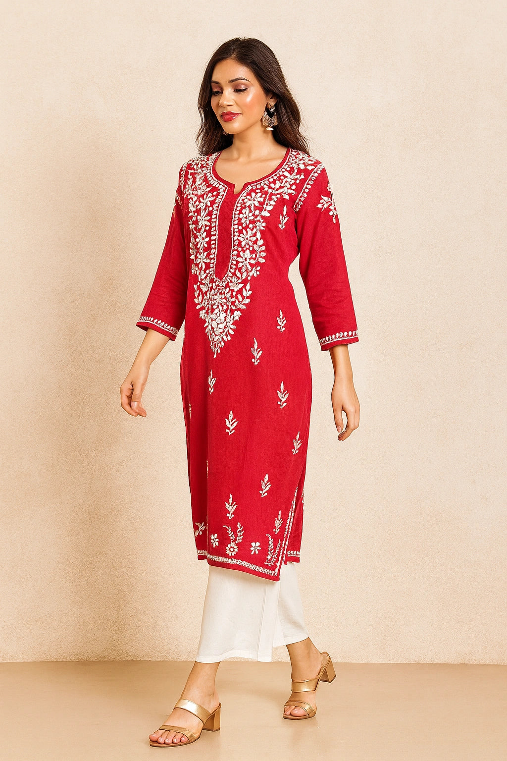 Woman wearing a red embroidered kurta with white pants on a beige background