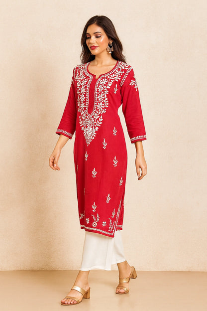 Woman wearing a red embroidered kurta with white pants on a beige background