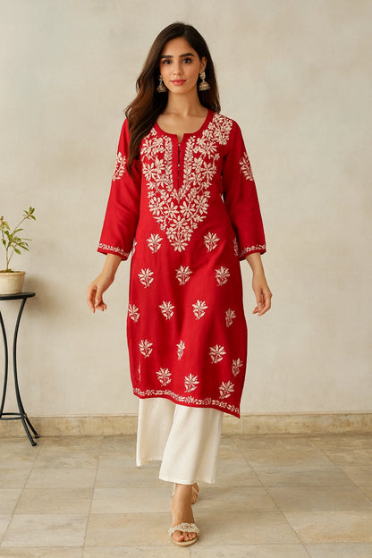Woman wearing a red embroidered kurta with white pants against a neutral background