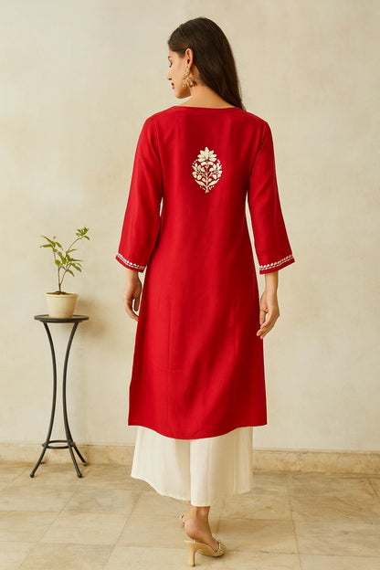 Woman wearing a red kurta with white embroidery in a minimal indoor setting