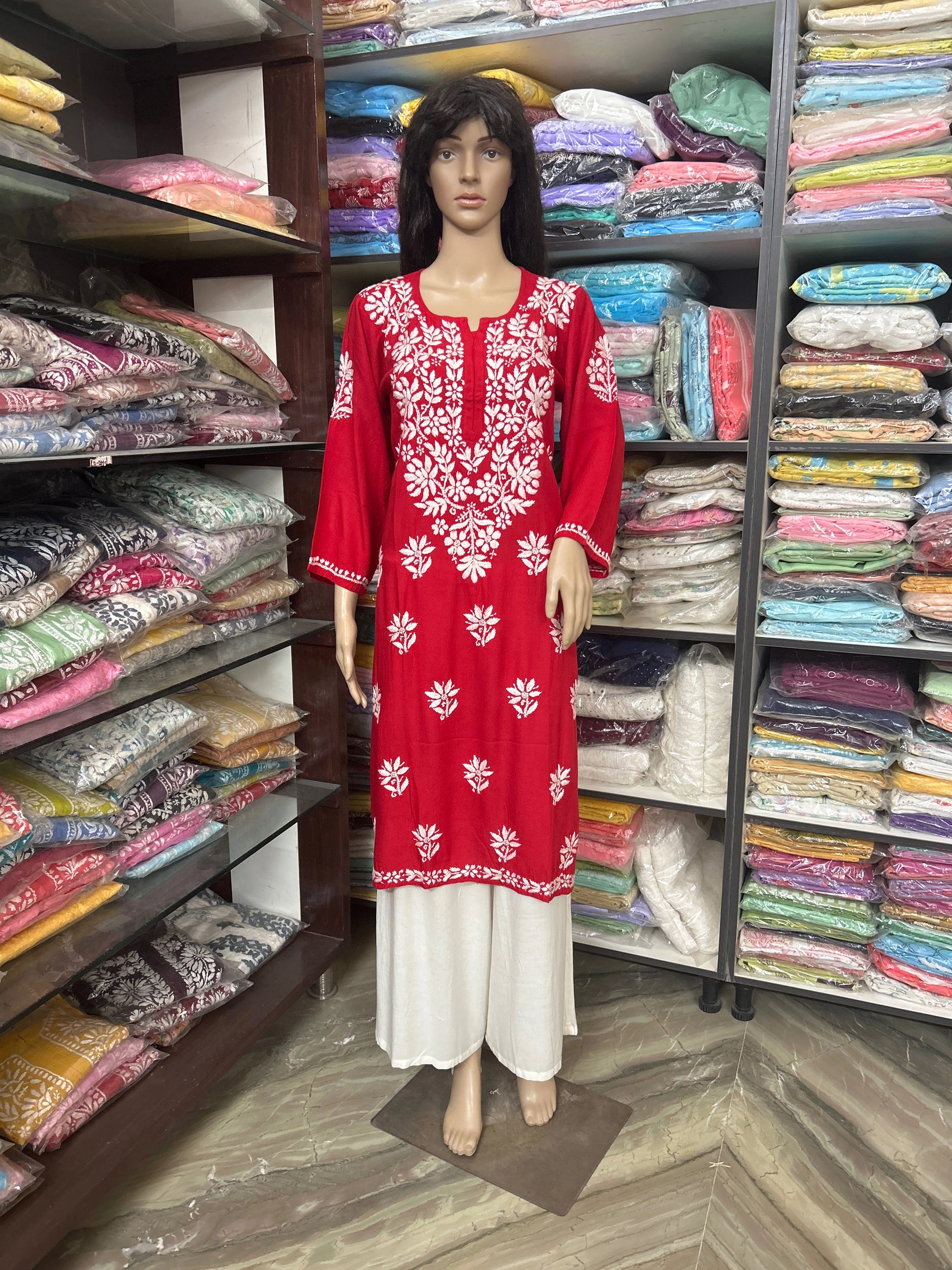 Mannequin wearing a red and white embroidered dress in a fabric store.