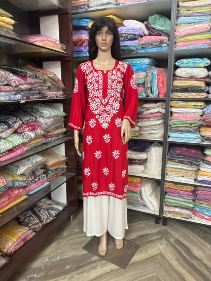 Mannequin wearing a red and white embroidered dress in a fabric store.
