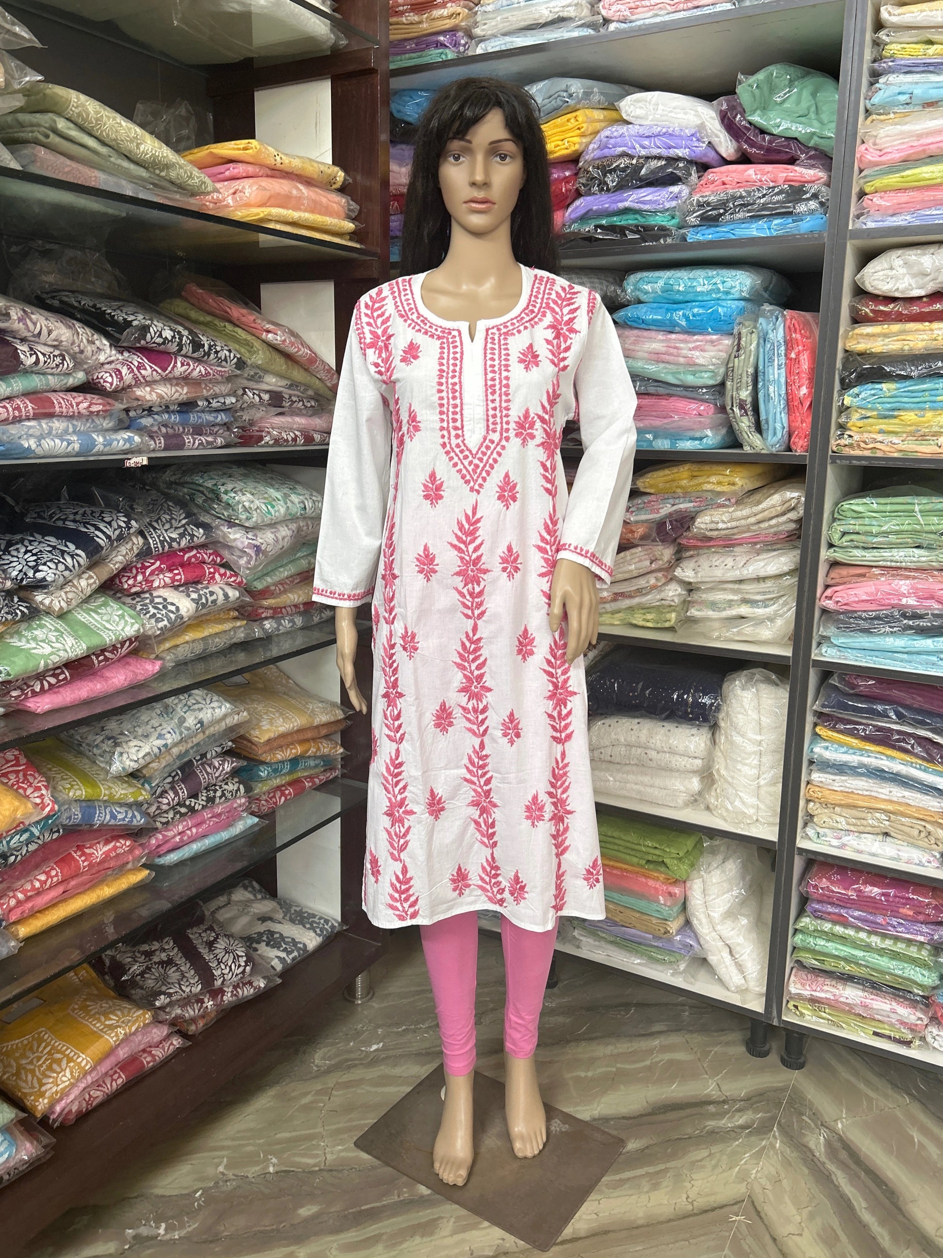 Mannequin wearing a white kurta with pink embroidery in a fabric store.
