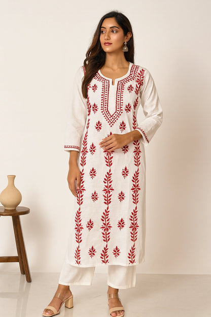 Woman wearing a white kurta with red floral embroidery on a plain background