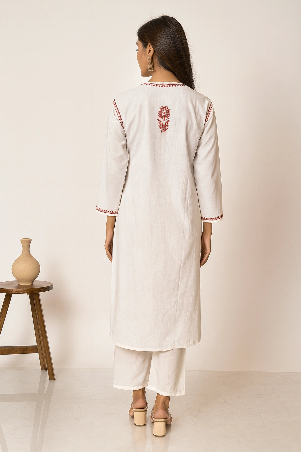 Woman wearing a white kurta with red embroidery in a minimalistic setting