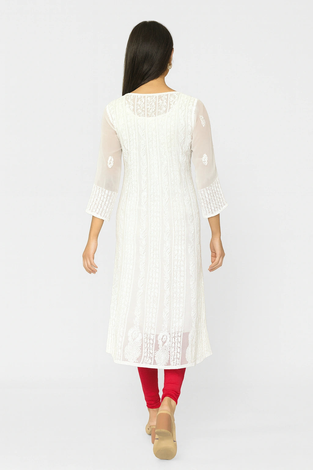 Woman wearing a white embroidered kurta with red leggings on a white background