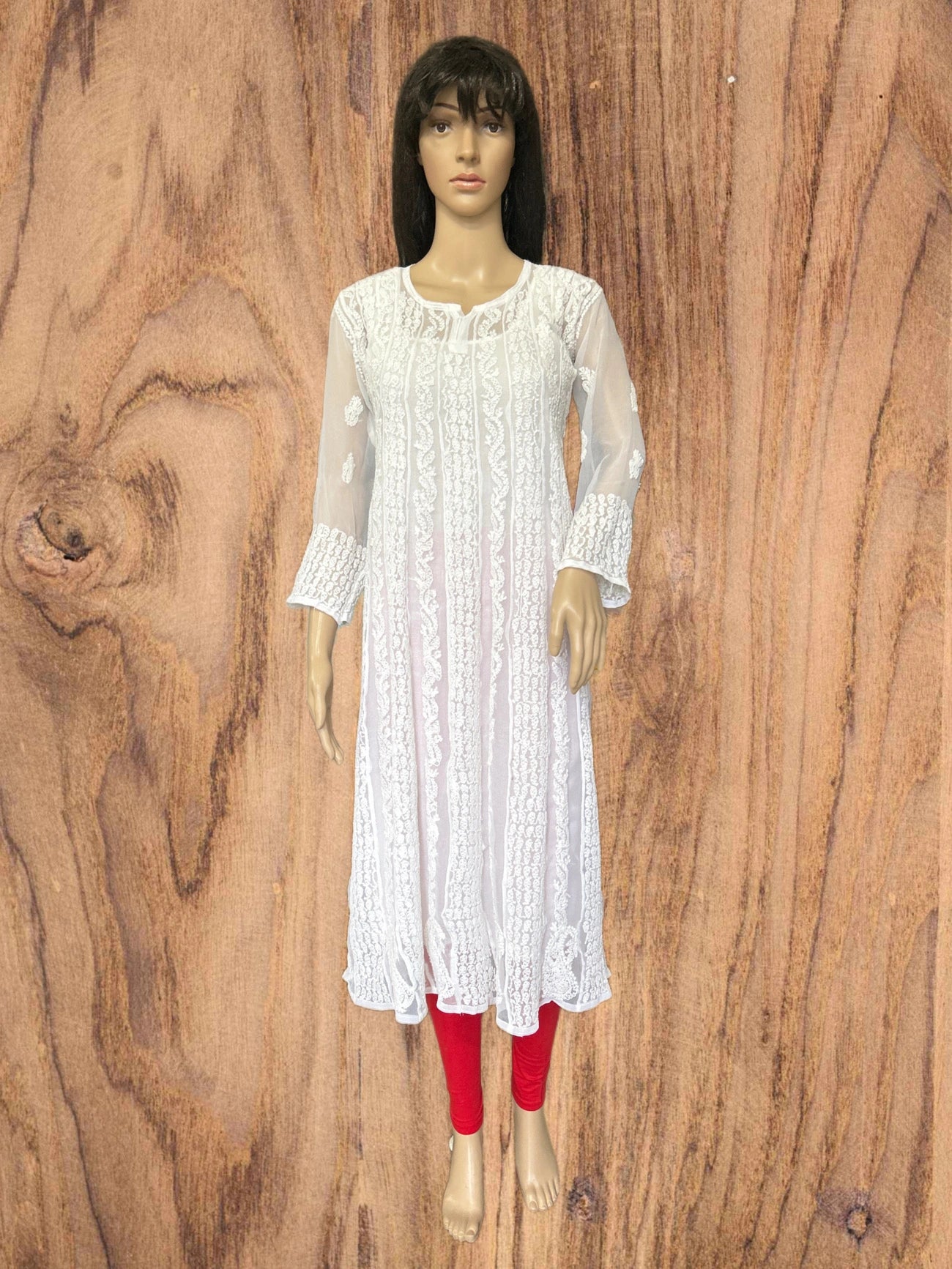 lucknowi chikankari Mannequin wearing a white lace dress with red leggings on a wooden background