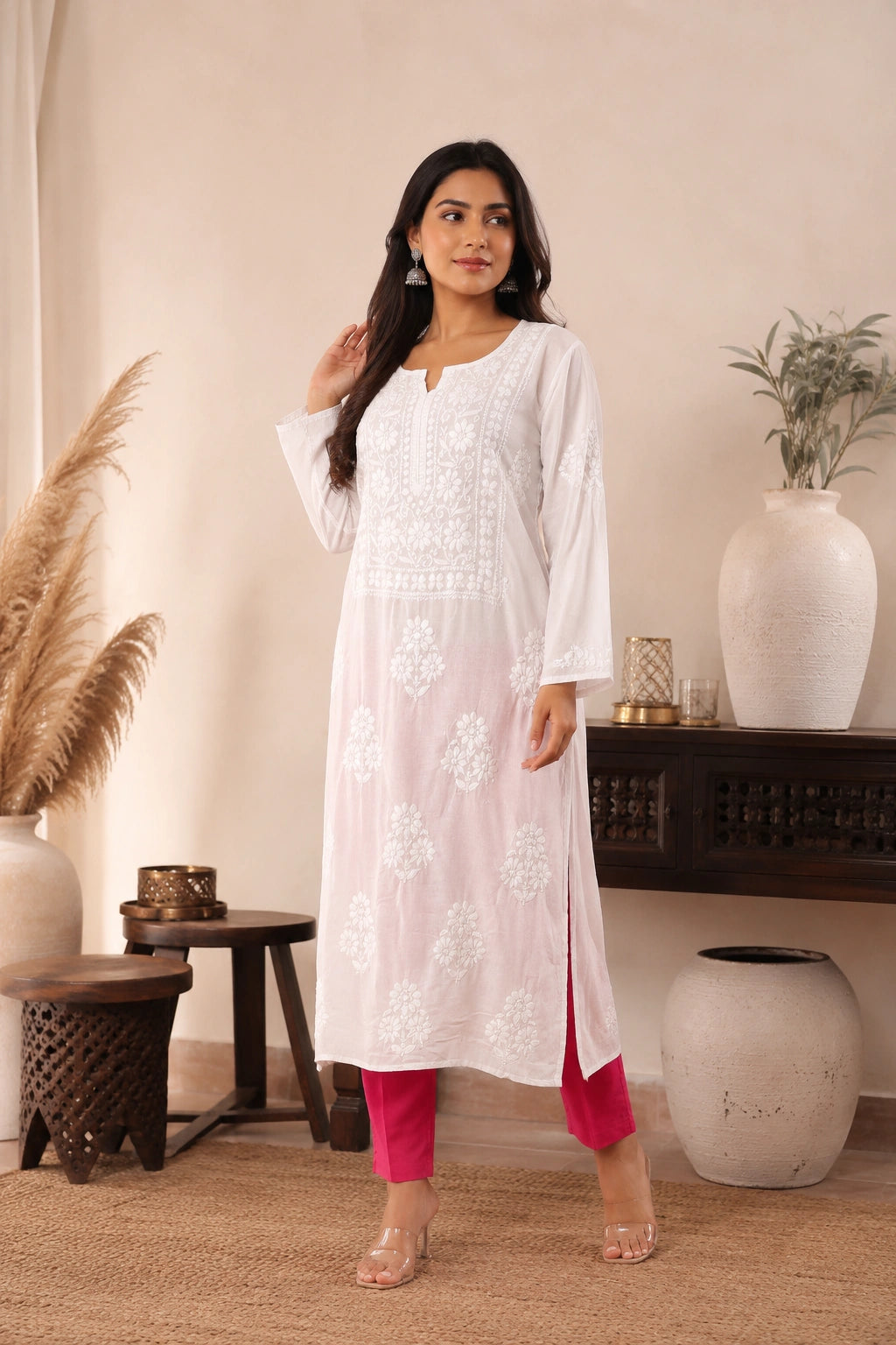 Woman wearing a white embroidered kurta with pink pants in a home setting.