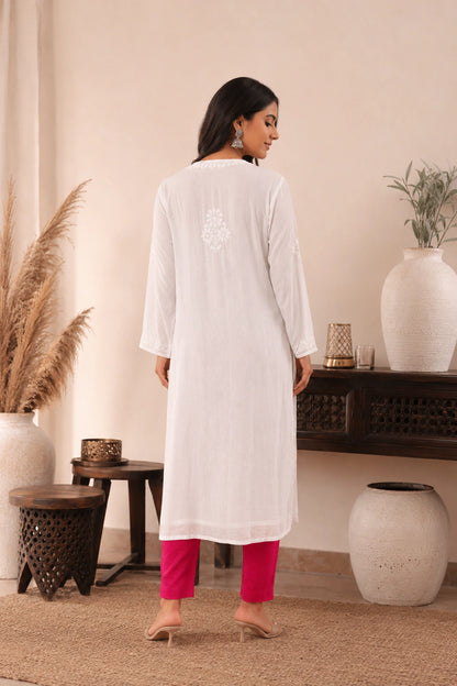 lucknowi chikankari Woman wearing a white kurta with pink pants in a home setting