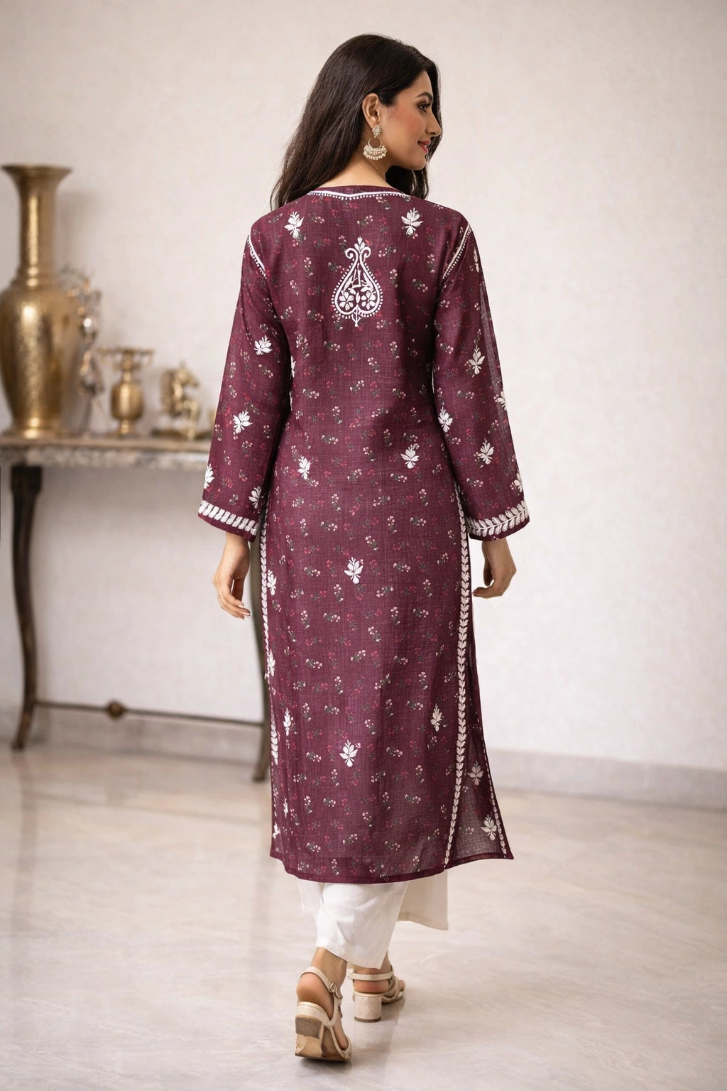 Woman wearing a maroon embroidered kurta with white pants in an indoor setting.