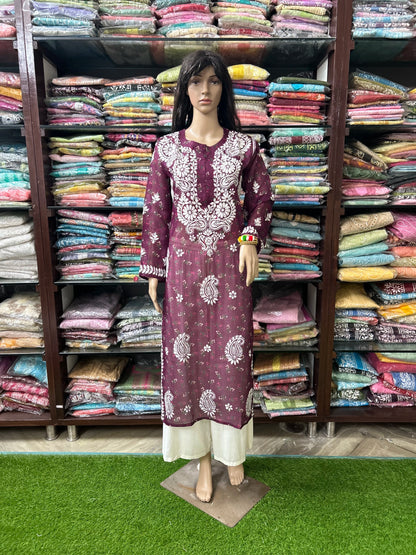 lucknowi chikankari Mannequin wearing a patterned dress in front of shelves filled with colorful fabrics.