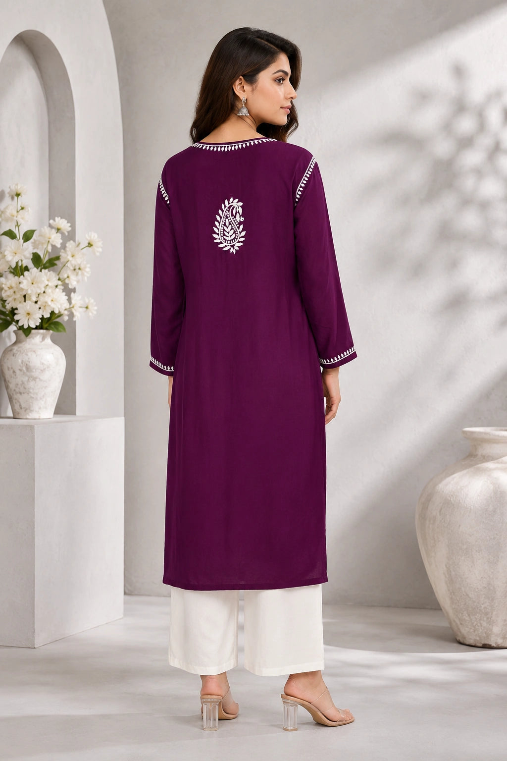 lucknowi chikankari Woman wearing a purple embroidered kurta with white pants in a minimalistic setting.