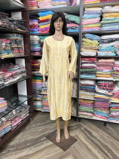 lucknowi chikankari Mannequin wearing a yellow dress in a fabric store with shelves of colorful fabrics.