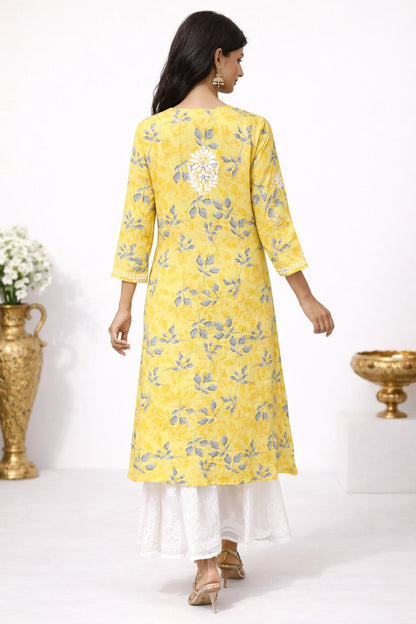 Woman wearing a lucknowi chikankari yellow floral kurta with white pants against a white background
