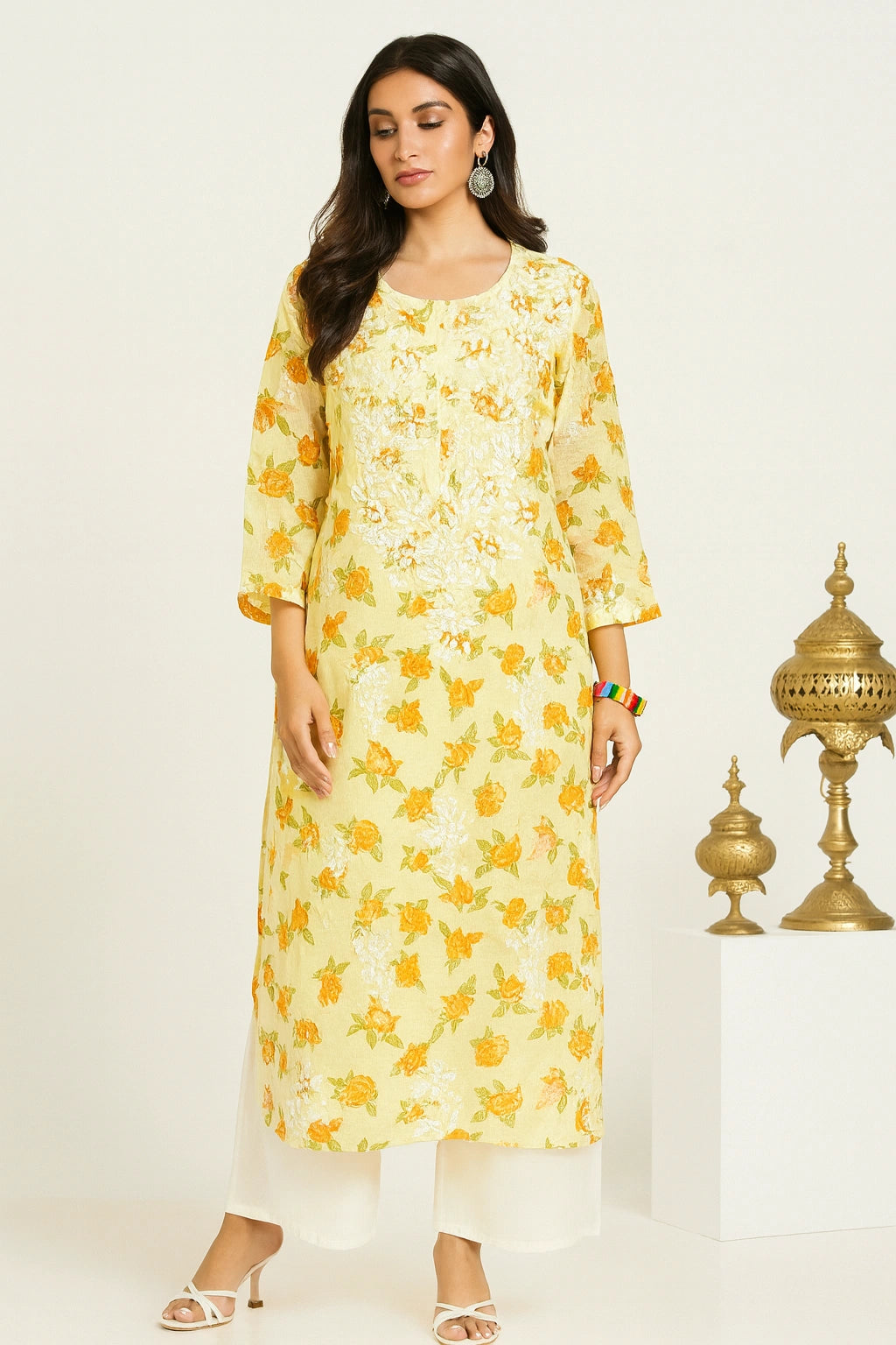 lucknowi chikankari Woman wearing a yellow floral dress with decorative lamps in the background