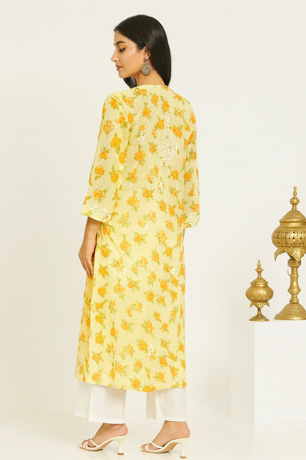 lucknowi chikankari Woman wearing a yellow floral kurta with white pants against a beige background