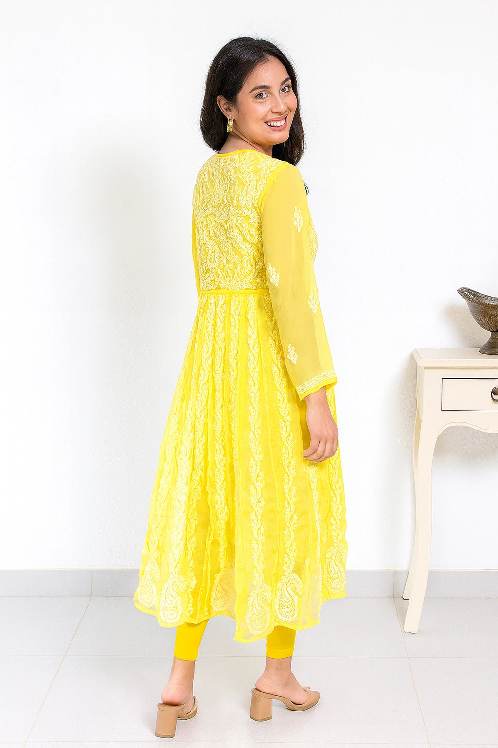 lucknowi chikankari Woman wearing a yellow dress with lace details on a white background