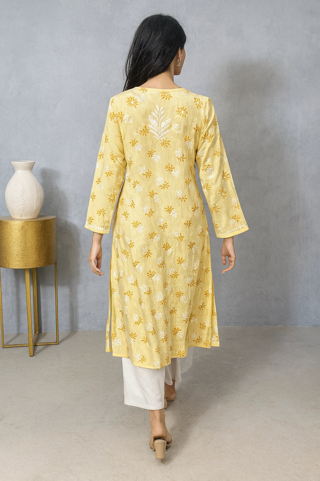 lucknowi chikankari Woman wearing a yellow floral kurta with white pants against a gray background