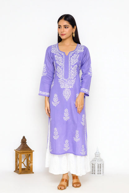 A woman modeling a lavender purple kurta with white floral embroidery, paired with a white skirt, standing against a white studio background with decorative lanterns.