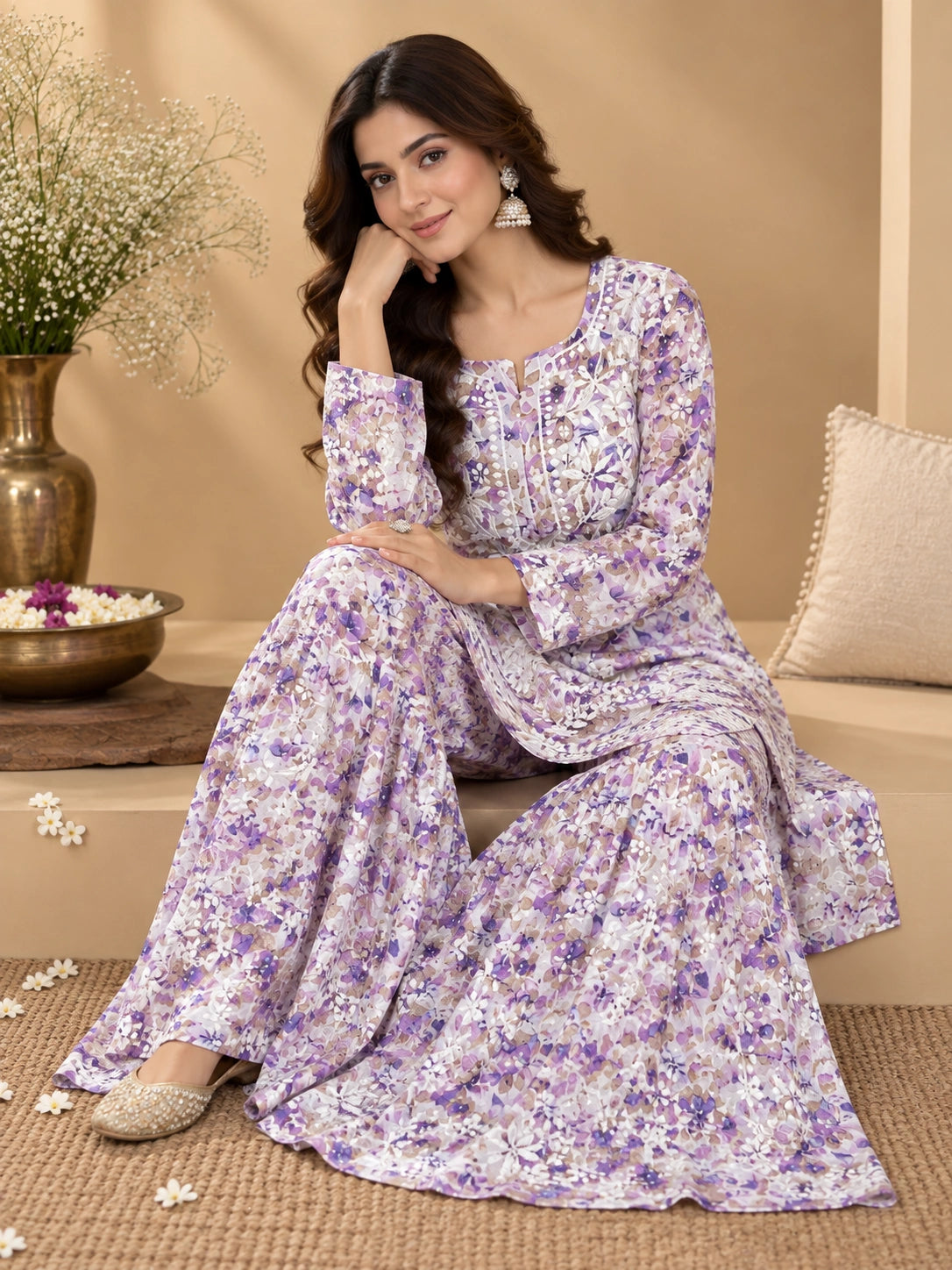 Lucknowi chikankari A woman models a lavender and purple floral print kurta set with matching wide-leg trousers in a warm, beige-toned indoor setting.